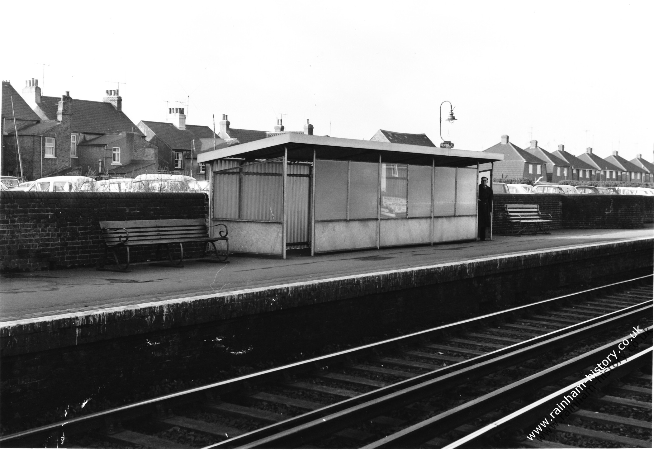 London bound platform with a solitary passenger waiting in the somewhat shabby looking shelter on the platform. You can see the new looking houses on Tufton Road in the distance